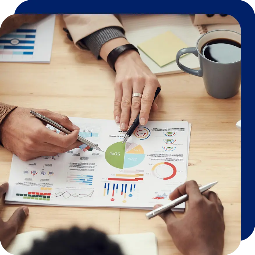 Close-up of hands pointing at colorful charts and graphs on a printed report during a business meeting