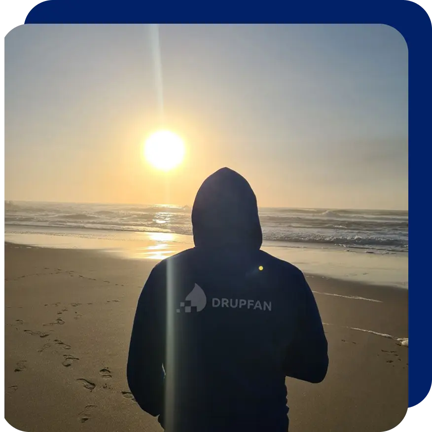 Person wearing a corporate hoodie standing on a beach.
